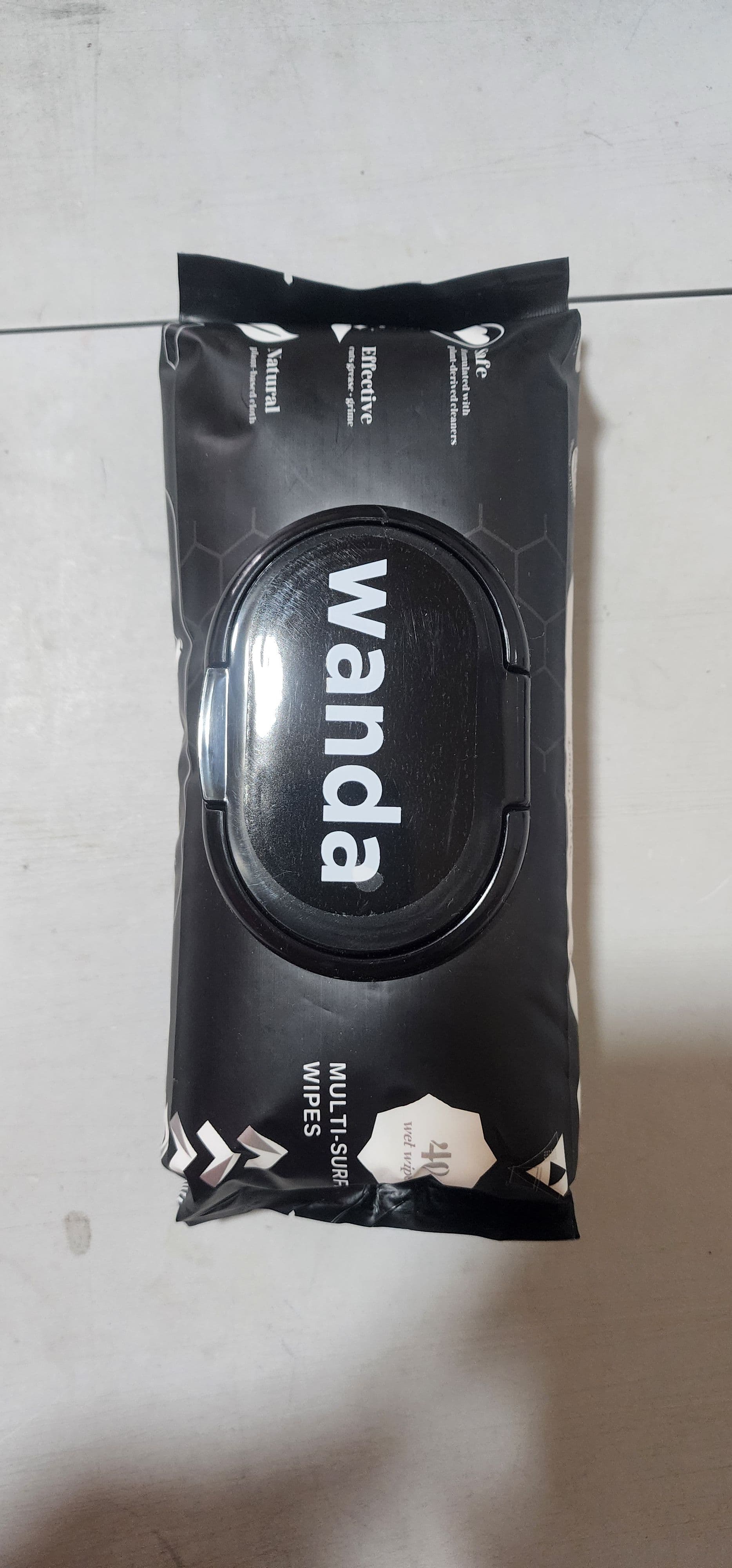 Black flexible pouch of Wanda Multi-Surface Wet Wipes, featuring a hard plastic flip-top dispenser lid and white text indicating 'Natural', 'Effective', and '40 wet wipes'.
