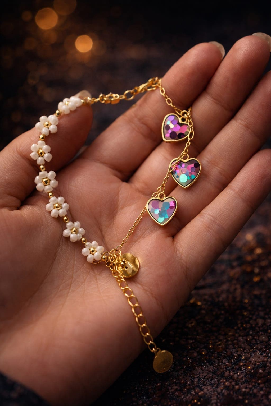 Gold chain bracelet with white beaded daisy flowers and three iridescent heart charms