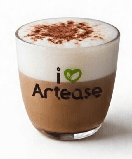 A layered coffee beverage, likely a cappuccino or latte, served in a clear glass tumbler with a thick layer of white foam topped with cocoa powder, featuring an 'i Artease' logo with a green leaf design printed on the glass.